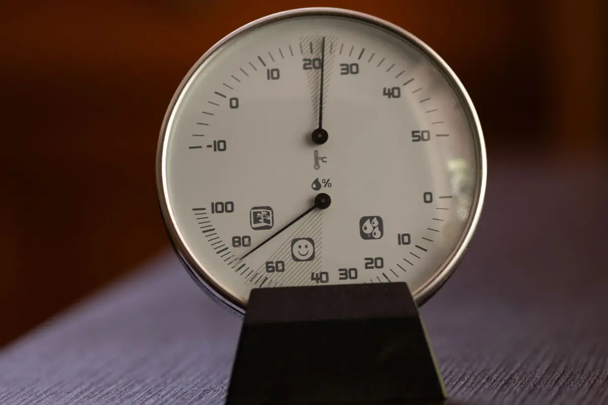 Analog hygrometer and thermometer dial on a wooden surface