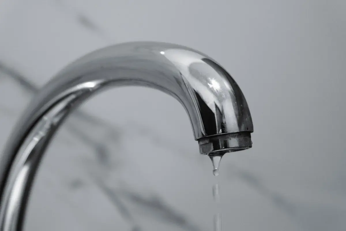 Water dripping from a chrome bathroom faucet over a gray marble counter